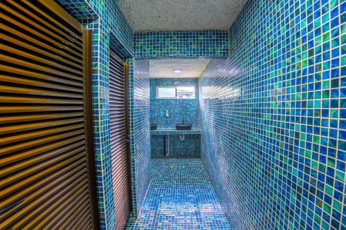 a blue tiled bathroom with a toilet and a sink at The Social Fortuna in Fortuna