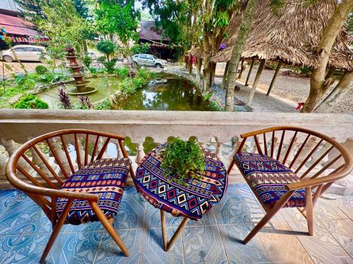 two chairs sitting on a porch with a pond at Homestay River Green in Làng Lap