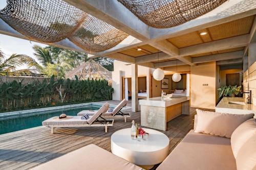 an outdoor living room with a pool and a villa at Salty Breeze Amed in Ambat