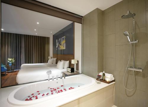 a bathroom with a bath tub and a bed at Le Palmier Ho Tram Resort - Beachfront with Private Beach in Ho Tram