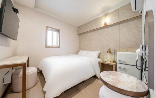 a hotel room with a white bed and a table at the stay in Seoul