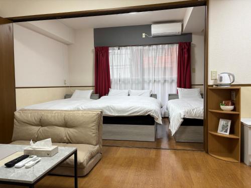 a hotel room with two beds and a couch at Laforet Tokaichi in Hiroshima