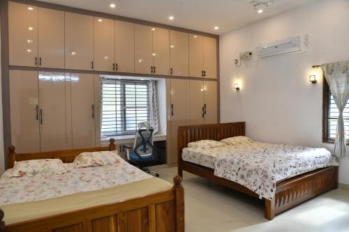 a bedroom with two beds and cabinets at Aadhya Abode Holiday Home in Kanyakumari