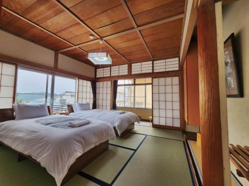 a bedroom with two beds in a room with windows at Snow Monkey Lodge in Yamanouchi