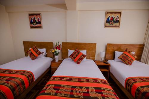 two twin beds in a room with flowers on the wall at Quechua Hostal Recoleta in Cusco