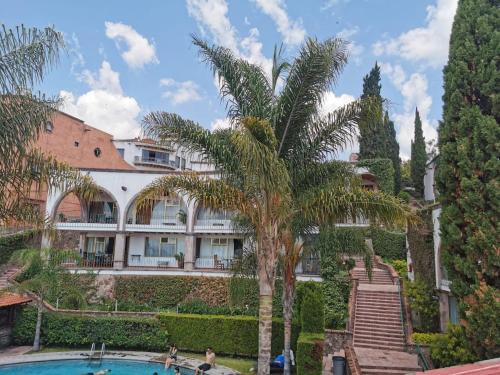 a building with a palm tree and a swimming pool at hotel la ermita suites in San Miguel de Allende