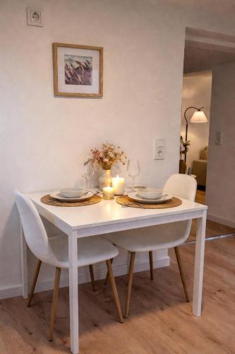 a white dining room table with two chairs and a vase of flowers at Cozy Suite Kirchheim, Parkplatz, Nähe A8, Souterrain in Kirchheim unter Teck