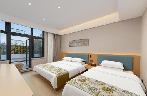 two beds in a hotel room with windows at Shiershan · Yuntang Hotel in Qingdao