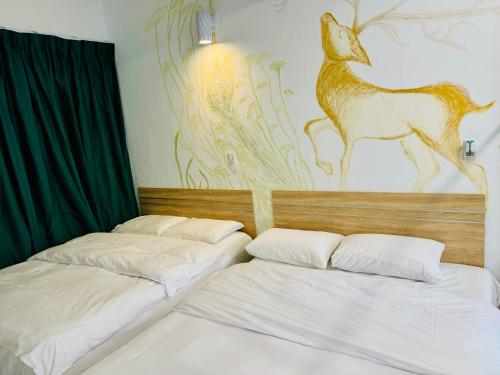 two beds in a room with a painting on the wall at 易民宿 Min su ji in Tainan