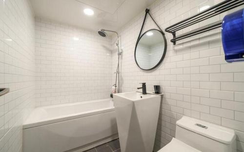 a white bathroom with a tub and a toilet and a mirror at My 24 Motel in Incheon