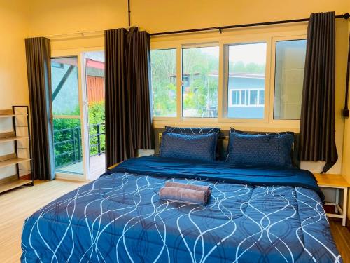 a bedroom with a bed with a blue comforter and windows at Thawat Villa Boutique Resort in Ko Lanta