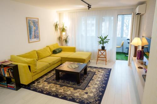 a living room with a yellow couch and a coffee table at D-home in Sofia