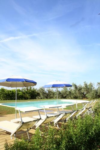 a group of chairs and umbrellas next to a swimming pool at Agriturismo SS Annunziata in San Vincenzo