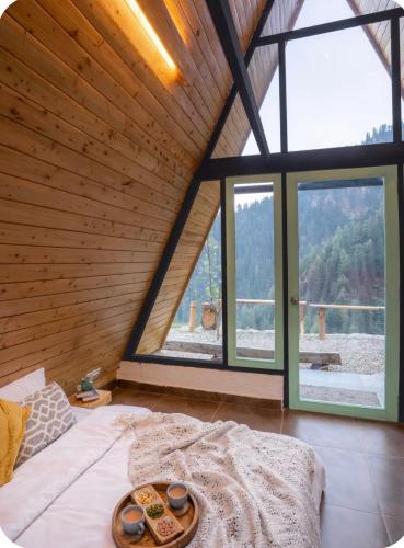 a room with a bed in a room with windows at The Crystal Cabin in Jibhi