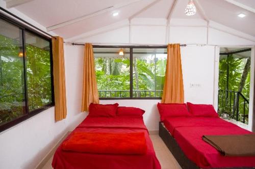 a room with two red beds and windows at Deep Villa in Batheri