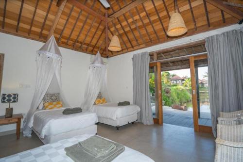 a bedroom with two beds and sliding glass doors at Harmony Heaven Ubud by The Travel Ubud Bali in Ubud