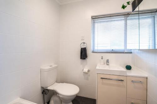 a white bathroom with a toilet and a sink at Urban Beach Shack - Steps to Grange Beach & Café in Grange