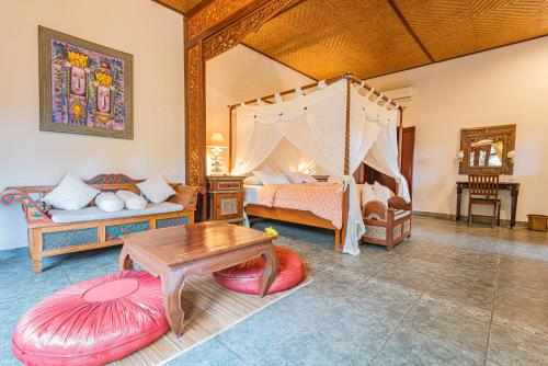 ein Schlafzimmer mit Himmelbett und Tisch in der Unterkunft Rambutan Hotel in Lovina