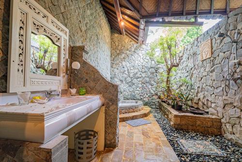 ein Badezimmer mit Waschbecken und einer Steinwand in der Unterkunft Rambutan Hotel in Lovina