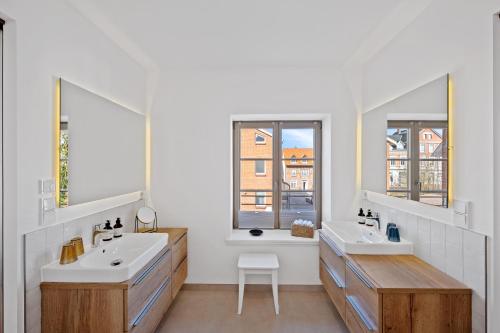 a bathroom with two sinks and two mirrors at ACKERBÜRGERHAUS - Historische Ferienwohnung mit 4 Schlafzimmern, Kamin, Sauna, Balkon-Terasse, Altstadt und See 5 Min zu Fuß, Moderne Küche, Parkplatz, WLAN in Eutin