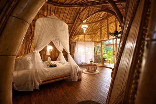 a bedroom with a canopy bed in a room at Hidden Bamboo Village in Sidemen