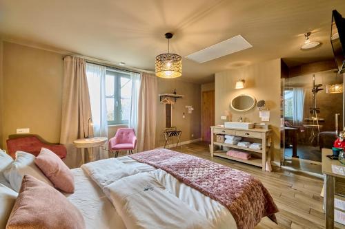 a bedroom with a large bed and a pink chair at B&B Rosteline in Hamont
