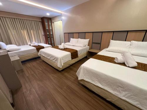 a hotel room with three beds in a room at Cambridge Guest House in Mandaue City