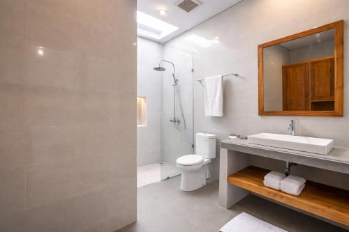 a bathroom with a sink and a toilet and a mirror at Villa Bawa in Ubud