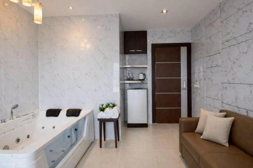 a large bathroom with a large tub and a couch at Sky dome resotel - โรงแรมสกายโดม รีโซเทล in Bangkok