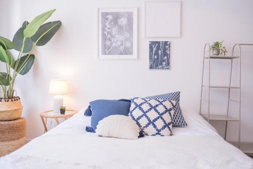 a bedroom with a white bed with blue pillows at Studio charmant au centre-ville in Charleroi