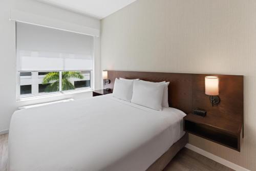 a bedroom with a large white bed and a window at Hyatt Place West Palm Beach in West Palm Beach