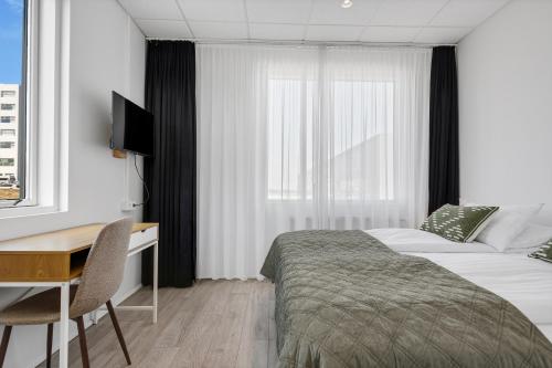 a hotel room with a bed and a desk and a window at ASKA Heiðmörk in Reykjavík
