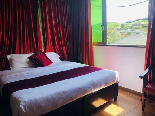 a bed in a room with a large window at Ghala Residency in Munnar