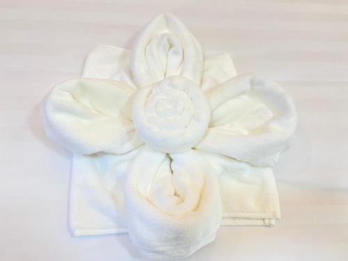 a white towel with a white flower on a table at Aten hotel in Sathani Khao Pip