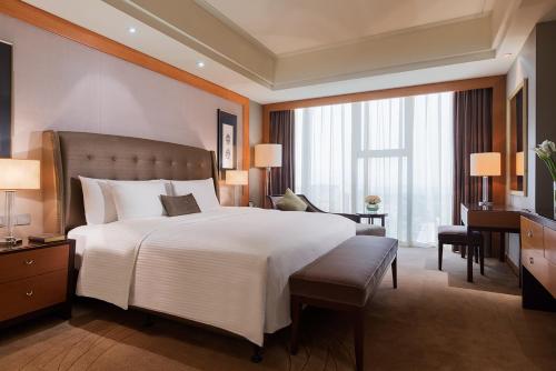 a bedroom with a large white bed and a desk at Wanda Realm Beijing in Beijing