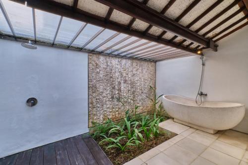 a bathroom with a bath tub in the corner of a building at Miko Villas Ubud in Ubud