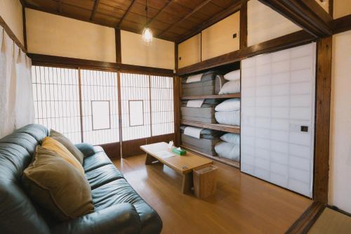 a living room with a leather couch and a table at Kominka Hakone Entire Traditional House in Hakone