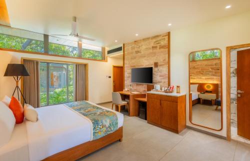 a bedroom with a bed and a desk with a computer at The Forest Chapter by Sayaji Sasan Gir in Chitrod