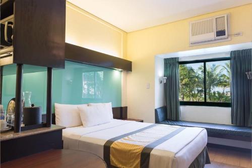 a hotel room with a bed and a window at Microtel by Wyndham Cabanatuan in Cabanatuan