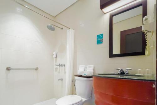 a bathroom with a toilet and a sink and a shower at Microtel by Wyndham Cabanatuan in Cabanatuan