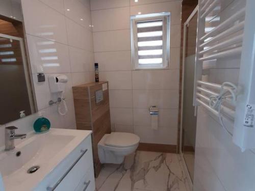 a white bathroom with a toilet and a sink at Repos Domki Łeba in Łeba