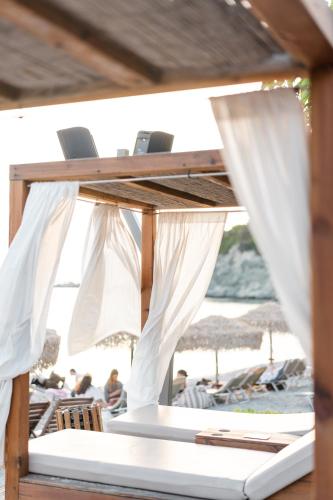 a table with white curtains and chairs on a beach at Vincci EverEden in Anavyssos