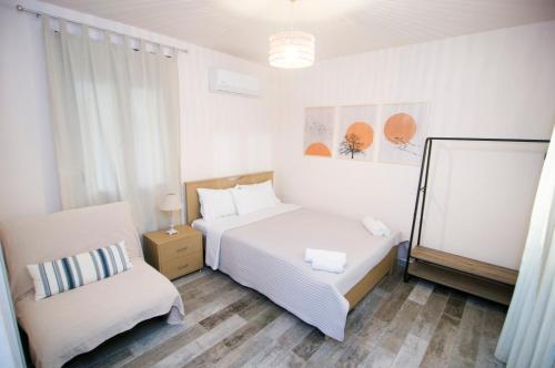 a white bedroom with a bed and a chair at Villa Saravari in Áyios Aléxandros