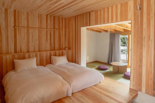 a bedroom with a large white bed and wooden walls at ホテル聚 - Hotel SHU in Tonosho