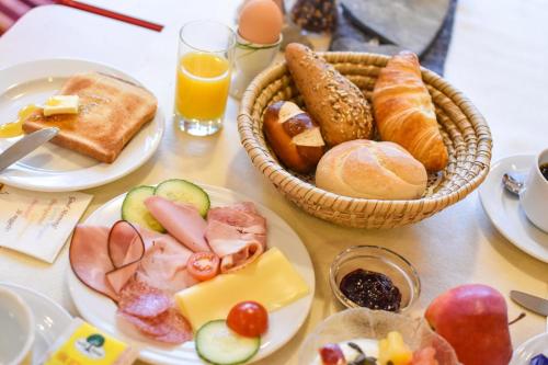a table with plates of food and baskets of breakfast foods at Berghotel Almrausch in Berwang