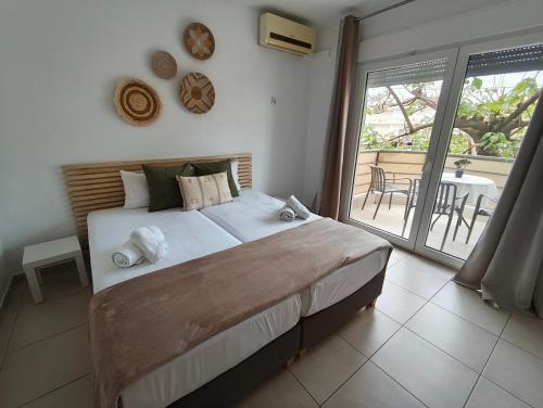 a bedroom with a large bed and a balcony at ILIDA apartments in Nea Peramos