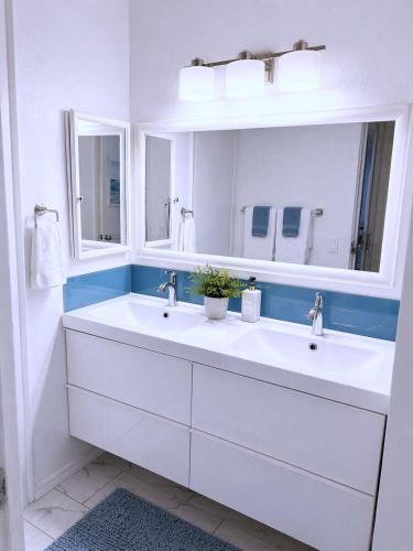 a white bathroom with two sinks and a mirror at SolMar Breeze - 1BR Condo at North Coast Village - Heated Pools, Hot Tubs & Steps to Beach, Oceanside Harbor and Pier in Oceanside