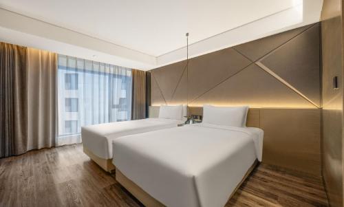 a bedroom with two beds and a large window at Mercure Harbin Central Street Sophia Church in Harbin