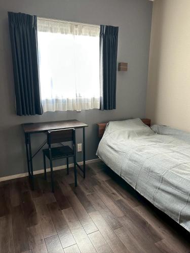 a bedroom with a desk and a bed and a window at Stella Casa in Gotemba