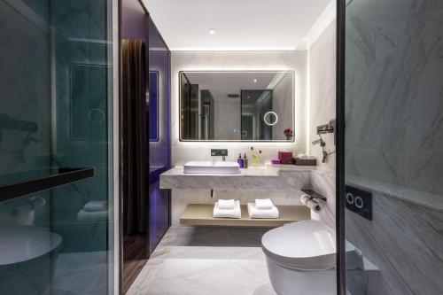 a bathroom with a sink and a toilet and a mirror at Mercure Harbin Central Street Sophia Church in Harbin